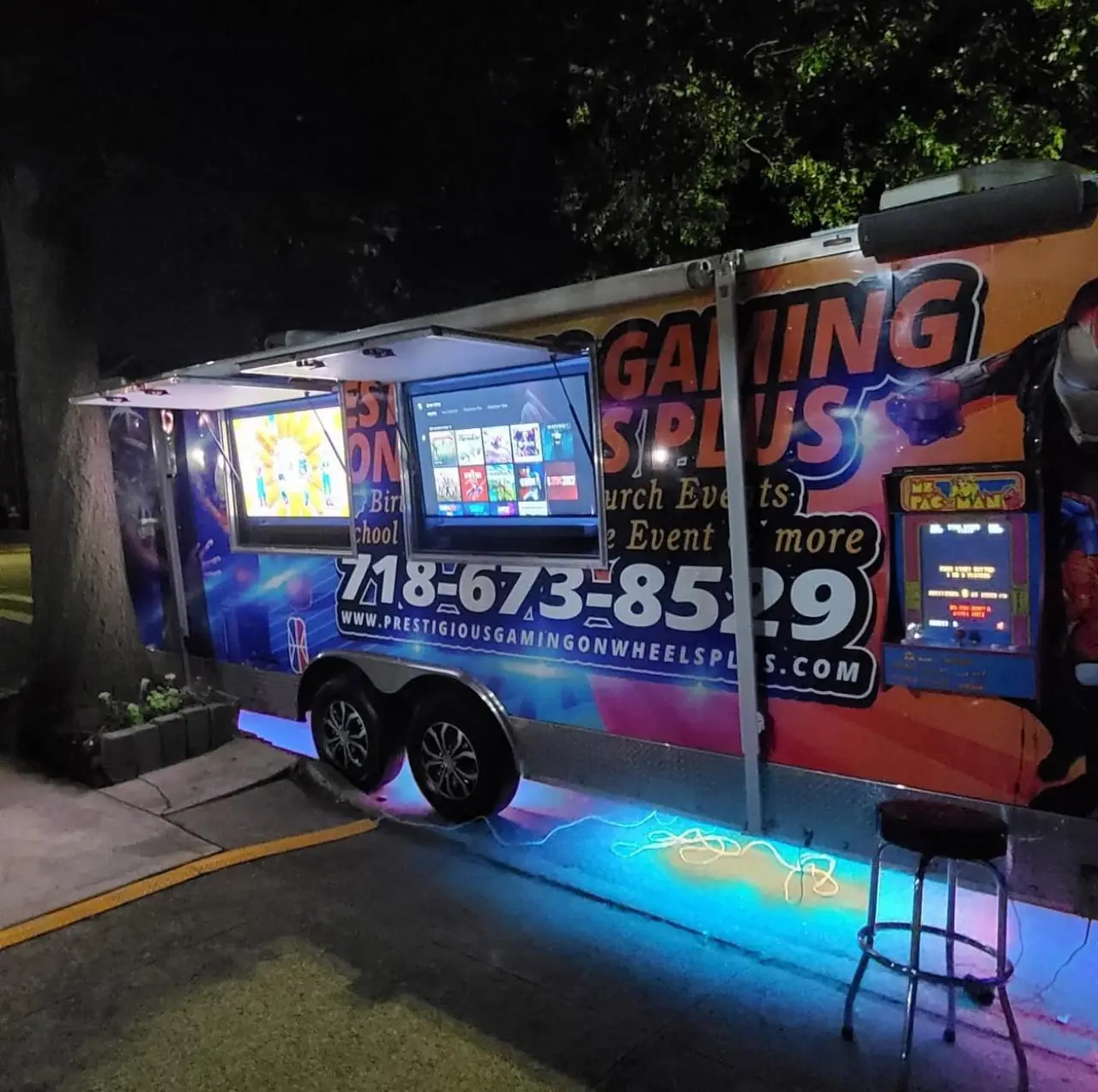 Prestigious Gaming on Wheels Plus trailer glowing with LED lights at a night party